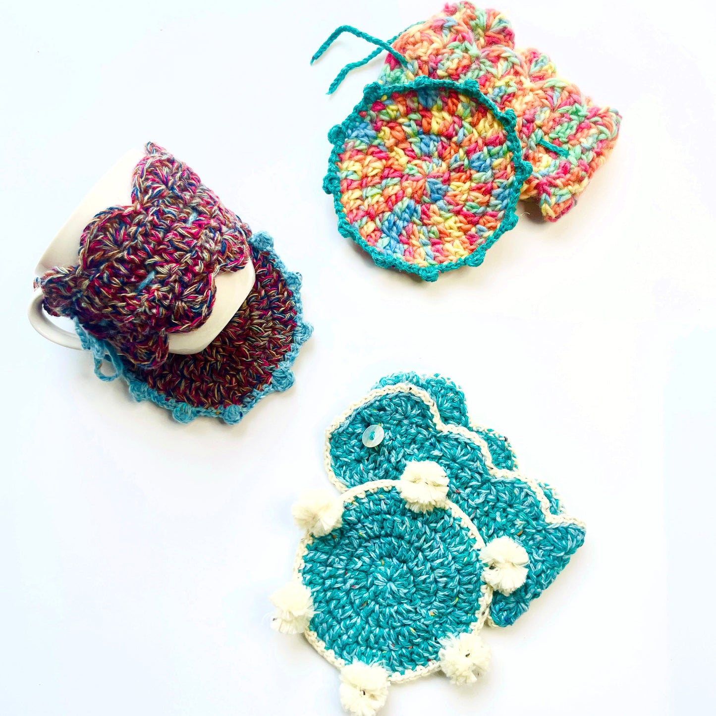 Colourful crochet coasters and mug wraps on a white background